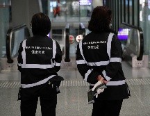 Oficiales de salubridad con escáneres de temperatura en el aeropuerto de Hong Kong. AP/A. Wong