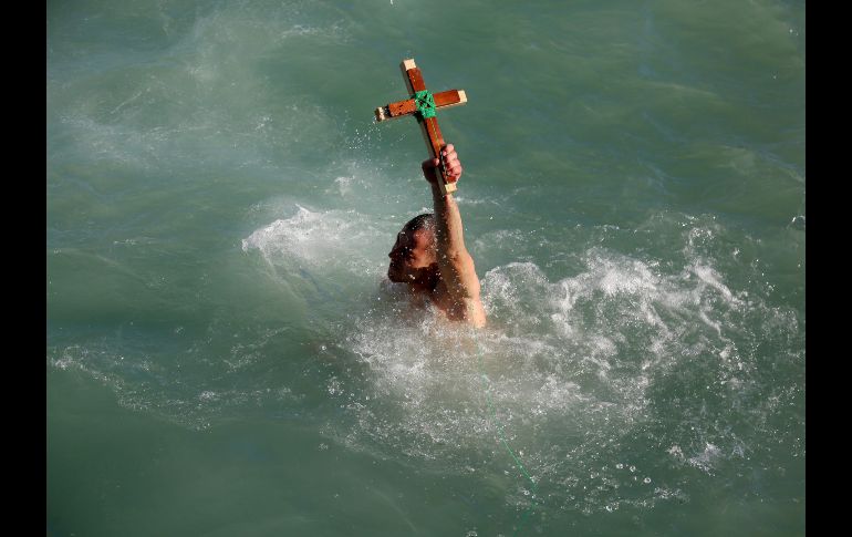 Se cree que quien recupere la cruz estará libre de espíritus malos y gozará de buena salud por todo el año. Nikolla Bici sostiene una cruz de madera en el mar Adriático en Durres, Albania. AFP/G. Shkullaku