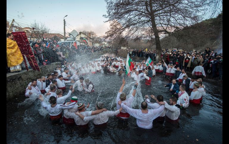 En Kalofer, Bulgaria, decenas de hombres vestidos con las tradicionales camisetas blancas bordadas se sumergen en el helado río de Tundzha. AP