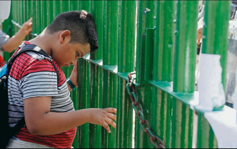Infancia en riesgo. Un niño se recarga sobre el portón que separa a Guatemala de la República Mexicana. EFE