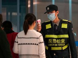 Personal del aeropuerto en Wuhan, China, checa la temperatura de pasajeros como parte de las medidas para frenar el brote del coronavirus. AP/D. Kang