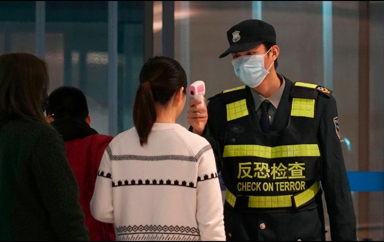 Personal del aeropuerto en Wuhan, China, checa la temperatura de pasajeros como parte de las medidas para frenar el brote del coronavirus. AP/D. Kang