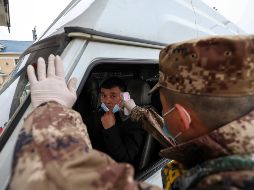 Un militar mide la temperatura de un conductor en un punto de revisión en una autopista en Wuhan, ciudad que suspendió desde hoy todos los transportes  para salir de la ciudad. AP/Chinatopix