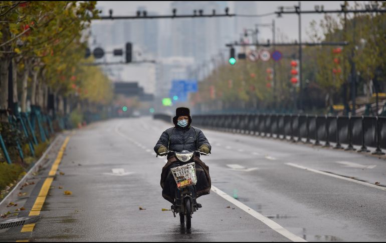 Un hombre conduce por una calle casi vacía en Wuhan. Autoridades decretaron medidas extremas frente al coronavirus como el cierre de los accesos a la ciudad, incluido el aeropuerto, y la suspensión de todos los servicios de transporte desde el 23 de enero. AFP/H. Retamal