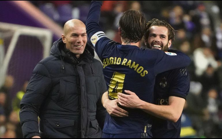 CELEBRACIÓN. Sergio Ramos abraza a Nacho, autor del gol madrileño, festejo al que se unió el DT Zinedine Zidane. AFP