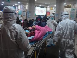 Personal médico durante el traslado de un paciente en el hospital de la Cruz Roja en Wuhan. El coronavirus ha dejado oficialmente 80 muertos en China, de un total de dos mil 744 casos confirmados. AFP/ARCHIVO