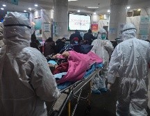 Personal médico durante el traslado de un paciente en el hospital de la Cruz Roja en Wuhan. El coronavirus ha dejado oficialmente 80 muertos en China, de un total de dos mil 744 casos confirmados. AFP/ARCHIVO