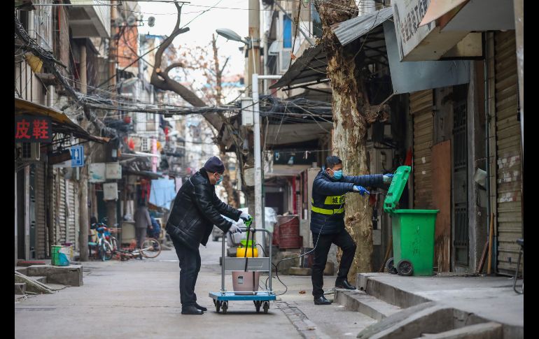 Empleados del gobierno echan desinfectante a un bote de basura en Wuhan. Casi la totalidad de la provincia de Hubei, cuya capital es Wuhan, está aislada del mundo por orden de las autoridades para intentar frenar la epidemia. AP/Chinatopix