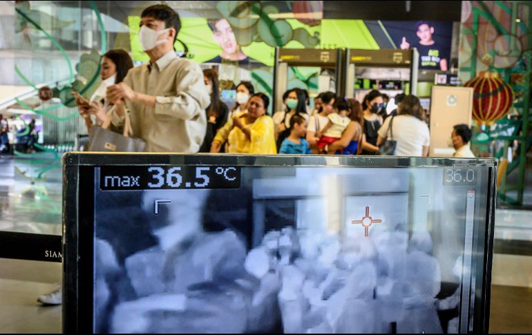 Personas pasan frente a un escáner que verifica la temperatura a la entrada de un centro comercial en Bangkok, Tailandia. AFP/M. Antonov