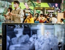 Personas pasan frente a un escáner que verifica la temperatura a la entrada de un centro comercial en Bangkok, Tailandia. AFP/M. Antonov