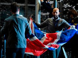 Empleados doblan una bandera del Reino Unido que hasta hace poco ondeaba en el Parlamento Europeo. AFP/J. Thys
