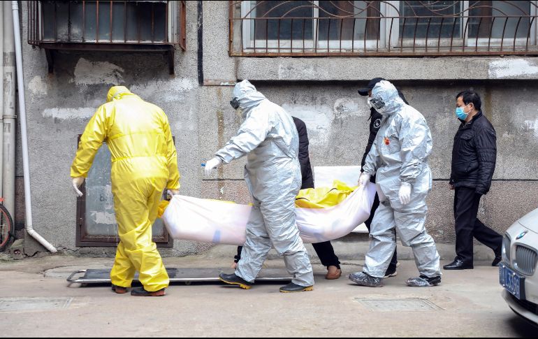 Trabajadores de una funeraria trasladan el cuerpo de una persona sospechosa de haber muerto de coronavirus en Wuhan, China. AP/Chinatopix