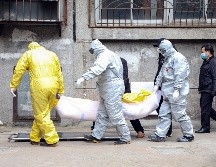 Trabajadores de una funeraria trasladan el cuerpo de una persona sospechosa de haber muerto de coronavirus en Wuhan, China. AP/Chinatopix