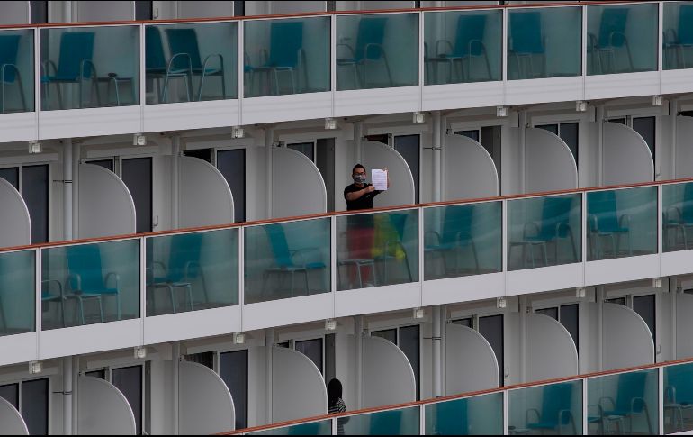 Un pasajero muestra un texto desde el crucero World Dream en Hong Kong, luego de que autoridades pusieron a la embarcación en cuarentena para prevenir el contagio del coronavirus. AP/V. Yu