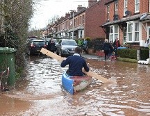 Un hombre usa una tabla de madera para remar un kayak para transportarse en medio de una calle inundada en Ross-on-Wye, al oeste de Inglaterra. AFP/O. Scarff