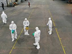 Trabajadores rocían hoy desinfectante en un centro de venta de productos agrícolas en Daegu. AP/Yonhap/Kim Hyun-tae