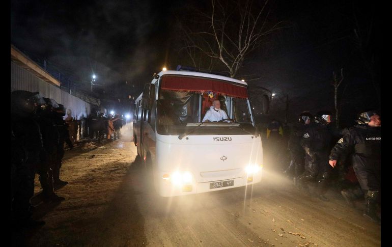 Policías abren paso a camiones con los ucranianos evacuados, rumbo al sanatorio donde pasarán la cuarentena en Novi Sanzhary. AFP