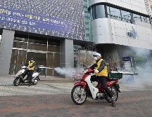 Personal de salud rocía desinfectante frente al templo Shincheonji en Daegu, Corea del Sur. AFP/Jung Yeon-je