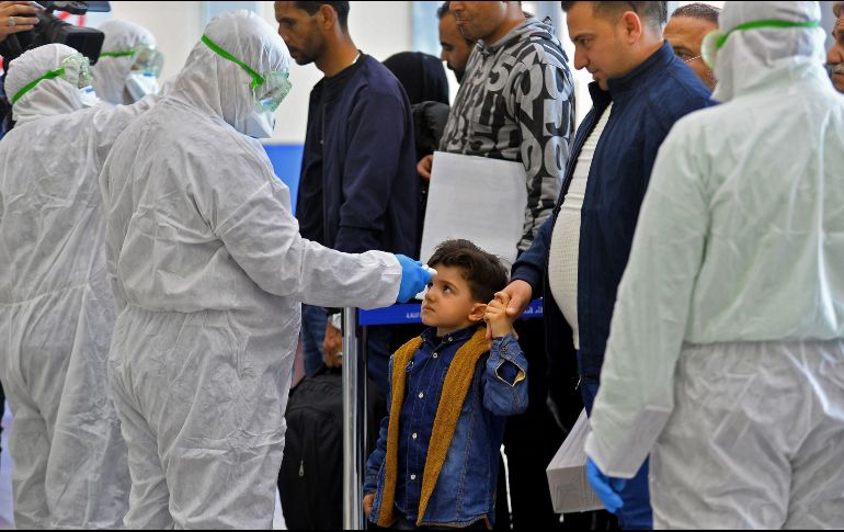 A un niño que regresa de Irán le toman la temperatura en el aeropuerto de Najaf, en Iraq. Autoridades toman medidas tras los nuevos casos de coronavirus. AFP/H. Hamdani