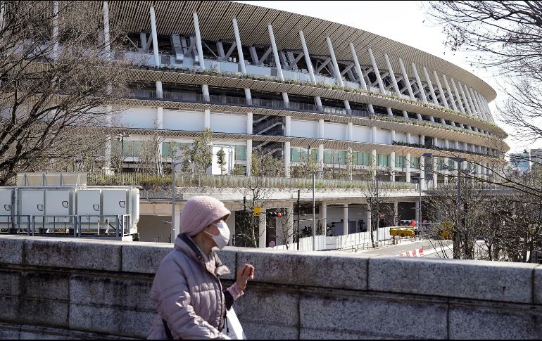 Una mujer con mascarilla pasa por el Estadio Nacional, donde será la apertura de los Juegos Olímpicos de Tokio. Hasta ahora los Juegos están programados para arrancar el 24 de julio. EFE/EPA/K. Mayama