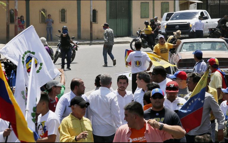 Imagenb que muestra a Juan Guaidó (c-d) mientras forma parte de un acto junto a sus seguidores, mientras motorizados encapuchados (atrás-i) los ahuyentan de la zona, en Barquisimeto. EFE/Oficina de Prensa de Guaidó