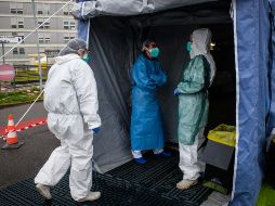 Trabajadores de la salud que usan trajes y máscaras protectoras entran a una unidad médica avanzada, construida frente al Hospital Cremona, en Italia. EFE/M. Corner
