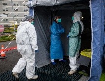 Trabajadores de la salud que usan trajes y máscaras protectoras entran a una unidad médica avanzada, construida frente al Hospital Cremona, en Italia. EFE/M. Corner