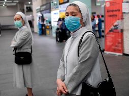 Dos monjas protegidas con cubrebocas aguardan en el Aeropuerto Internacional de la Ciudad de México. AFP/P. Pardo