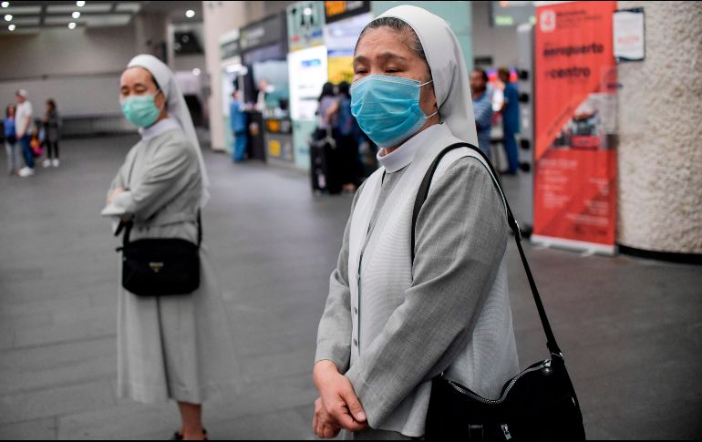 Dos monjas protegidas con cubrebocas aguardan en el Aeropuerto Internacional de la Ciudad de México. AFP/P. Pardo