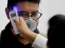 Trabajadores del Ministerio de Salud revisan la temperatura de pasajeros provenientes de un vuelo de España en el aeropuerto La Aurora, de Ciudad de Guatemala. EFE/E. Biba