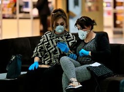 Dos mujeres con máscaras protectoras esperan su vuelo en el aeropuerto de Bagdad, en Iraq. AP/H. Mizban