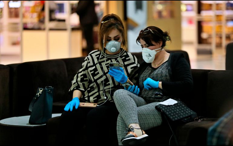 Dos mujeres con máscaras protectoras esperan su vuelo en el aeropuerto de Bagdad, en Iraq. AP/H. Mizban