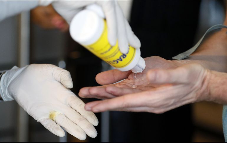 Una funcionaria de sanidad reparte gel antibacterial a los viajeros que llegan este jueves al aeropuerto internacional El Dorado, en Bogotá, Colombia. EFE/C. Ortega