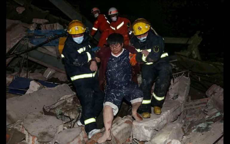 Trabajadores de rescate, vestidos con overoles anaranjados, trepan sobre escombros y estructuras metálicas retorcidas del hotel para sacar a las víctimas. AFP