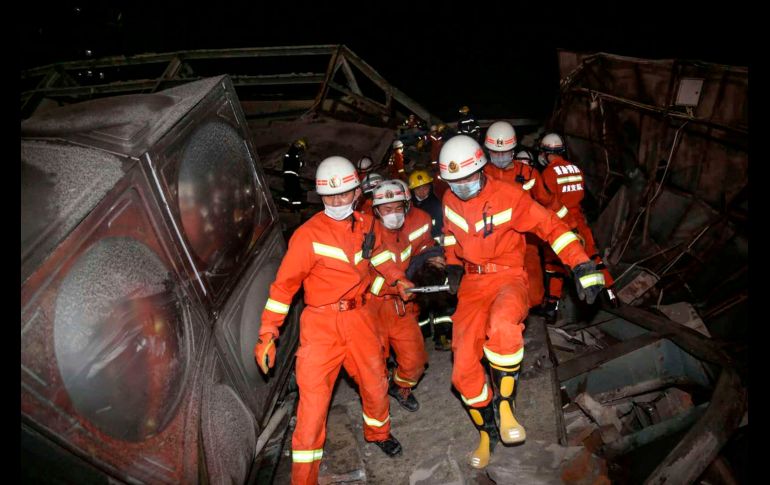 Trabajadores de rescate, vestidos con overoles anaranjados, trepan sobre escombros y estructuras metálicas retorcidas del hotel para sacar a las víctimas. AFP