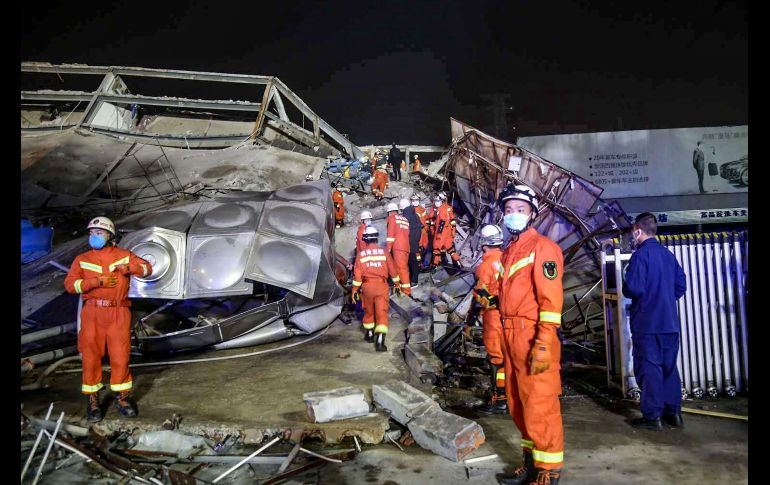 Trabajadores de rescate, vestidos con overoles anaranjados, trepan sobre escombros y estructuras metálicas retorcidas del hotel para sacar a las víctimas. AFP