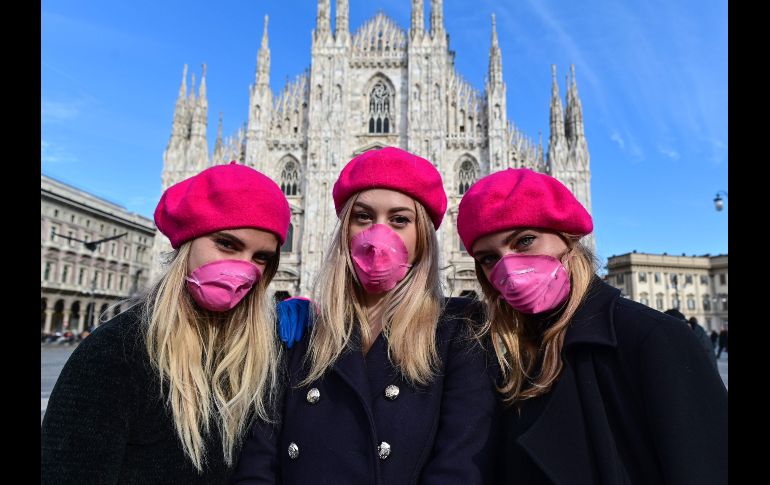 Mujeres con mascarillas rosas posan frente al Domo de Milán, en Italia, para conmemorar el 8M. AFP/M. Medina