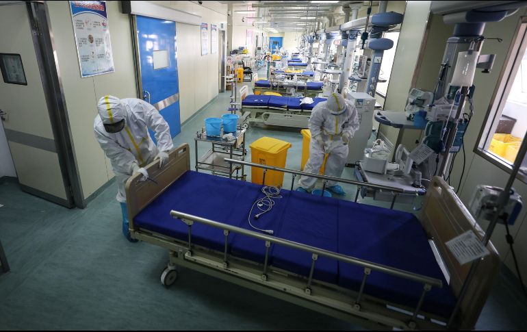 Personal médico mueve hoy una cama en una área vacía usada para atender solo a pacientes de covid-19 en un hospital en Wuhan. El hospital se prepara para acondicionar la zona para enfermos en general. AFP
