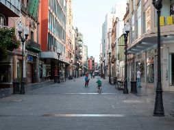 Unos niños juegan este sábado con sus bicicletas por la calle Triana, uno de los principales centros comerciales de Madrid que luce semivacío este sábado. EFE/A. Medina