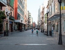 Unos niños juegan este sábado con sus bicicletas por la calle Triana, uno de los principales centros comerciales de Madrid que luce semivacío este sábado. EFE/A. Medina