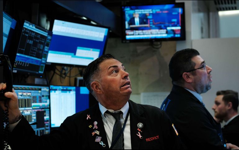 Corredores en la bolsa de Nueva York reaccionan mientras el presidente Trump habla  en rueda de prensa en la Casa Blanca. AFP/S. Platt