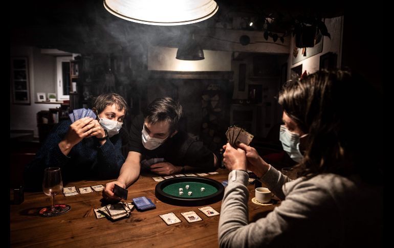 Una familia aislada en su domicilio juega cartas en Givors, Francia. AFP/J. Ksiazek