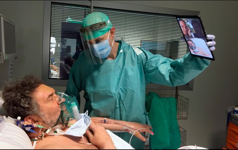 El doctor Matteo Flippini sostiene una tableta para que uno de sus pacientes pueda sostener una videollamada con sus seres queridos. AP/S. Cattaneo