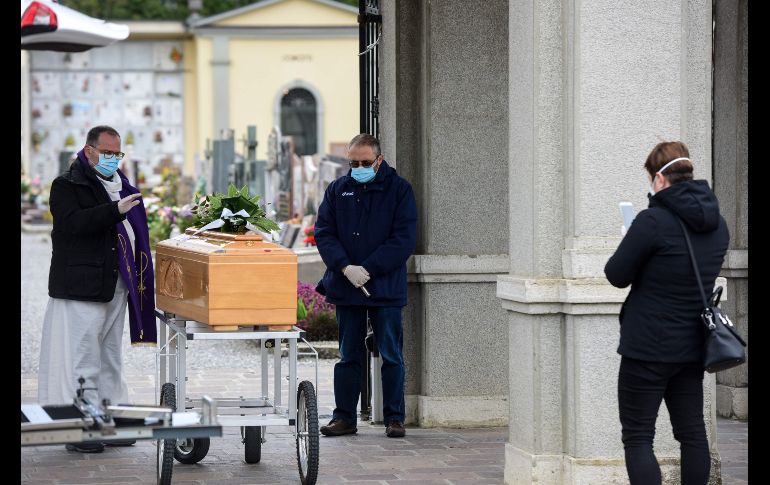 Un familiar de un fallecido graba el funeral para otro familiar que vive en Israel, en el cementerio de Bolgare, en Lombardía. AFP/C. Cruciati