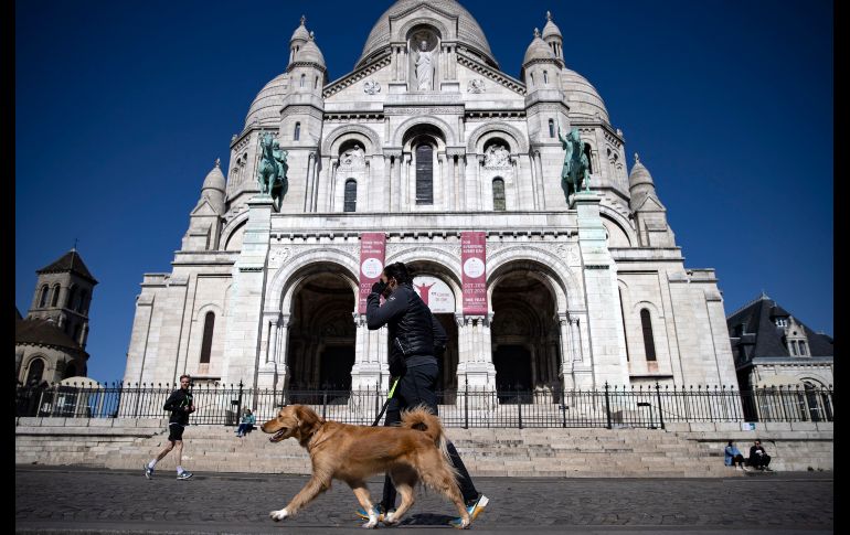 Un joven protegido con una mascarilla da un breve paseo a su perro por las calles semivacías de Montmartre. EFE/I. Langsdon
