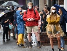 Varias personas protegidas con mascarillas caminan por calles de Australia. EFE/J. Carrett
