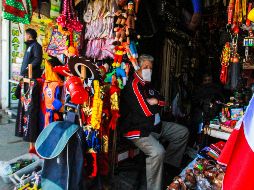 Una persona atiende su negocio de recuerdos protegida con un cubrebocas. XINHUA/J. Terriquez