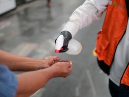 Personal de seguridad del Metro de la Ciudad de México desinfecta las manos de un usuario este martes. AFP/P. Pardo