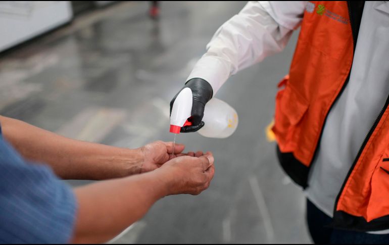 Personal de seguridad del Metro de la Ciudad de México desinfecta las manos de un usuario este martes. AFP/P. Pardo