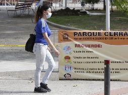 Una mujer camina al frente de un letrero que dice 